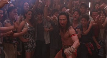 Movie still from “Hot Shots! Part Deux” (1993), directed by Jim Abrahams – A group of people in a room with a man in a fighting stance; Medium shot, High angle