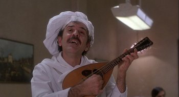 Movie still from “Hot Shots! Part Deux” (1993), directed by Jim Abrahams – A man in a chef's hat playing a guitar; Close Up shot, Low angle