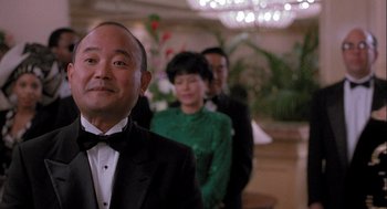 Movie still from “Hot Shots! Part Deux” (1993), directed by Jim Abrahams – A man in a tuxedo standing in front of two other people; Close Up shot, Low angle