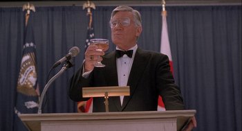 Movie still from “Hot Shots! Part Deux” (1993), directed by Jim Abrahams – A man in a tuxedo holding a glass of wine; Medium shot, Low angle