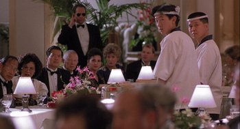 Movie still from “Hot Shots! Part Deux” (1993), directed by Jim Abrahams – A group of people sitting around a table; Medium shot, Over the shoulder angle
