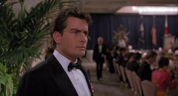 Movie still from “Hot Shots! Part Deux” (1993), directed by Jim Abrahams – A man in a tuxedo standing in front of a group of people; Close Up shot, Low angle
