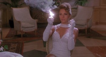 Movie still from “Hot Shots! Part Deux” (1993), directed by Jim Abrahams – A woman in a white dress holding a sparkler in her hand; Medium shot, Low angle