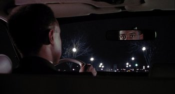 Movie still from “Hot Shots! Part Deux” (1993), directed by Jim Abrahams – A man driving a car at night in front of a mirror; Close Up shot, Over the shoulder angle