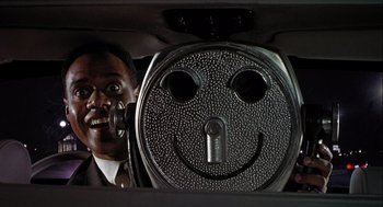 Movie still from “Hot Shots! Part Deux” (1993), directed by Jim Abrahams – A man in a car with a smiley face on the window; Close Up shot, Low angle