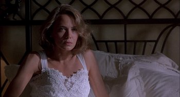 Movie still from “Hot Shots! Part Deux” (1993), directed by Jim Abrahams – A woman sitting on a bed in front of a window; Close Up shot, Low angle