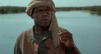 Movie still from “Hot Shots! Part Deux” (1993), directed by Jim Abrahams – A man with a turban is standing in front of a body of water; Close Up shot, Low angle