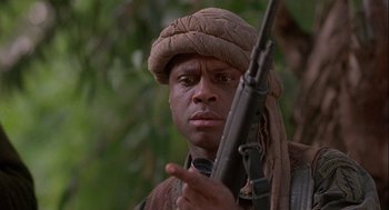 Movie still from “Hot Shots! Part Deux” (1993), directed by Jim Abrahams – A man holding a rifle in a forest; Close Up shot, Low angle