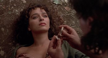 Movie still from “Hot Shots! Part Deux” (1993), directed by Jim Abrahams – A woman laying on the ground while a man holds a piece of paper in front of her face; Close Up shot, Overhead angle