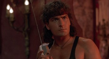 Movie still from “Hot Shots! Part Deux” (1993), directed by Jim Abrahams – A man holding a cell phone while wearing a black tank top; Close Up shot, Low angle