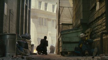 Movie still from “Hotel Artemis” (2018), directed by Drew Pearce – A man kneeling down on the ground near a building; Wide shot, High angle