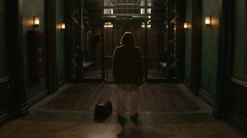 Movie still from “Hotel Artemis” (2018), directed by Drew Pearce – A person standing in a room with a suitcase; Wide shot, High angle