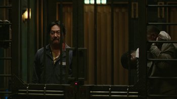 Movie still from “Hotel Artemis” (2018), directed by Drew Pearce – A man standing in front of a metal fence; Medium shot, Low angle