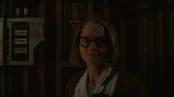Movie still from “Hotel Artemis” (2018), directed by Drew Pearce – A woman wearing glasses standing in front of a wooden wall; Close Up shot, Low angle