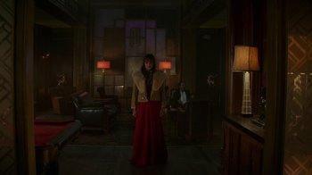 Movie still from “Hotel Artemis” (2018), directed by Drew Pearce – A woman standing in a room with a man sitting in the background; Wide shot, Low angle