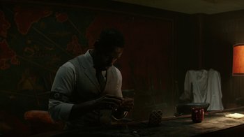 Movie still from “Hotel Artemis” (2018), directed by Drew Pearce – A man in a white jacket is looking at a cell phone; Medium shot, Over the shoulder angle