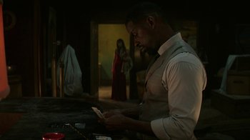Movie still from “Hotel Artemis” (2018), directed by Drew Pearce – A man looking at a cell phone in front of a woman; Medium shot, Over the shoulder angle