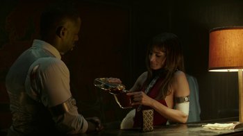 Movie still from “Hotel Artemis” (2018), directed by Drew Pearce – A man and a woman at a table with boxes; Medium shot, Over the shoulder angle