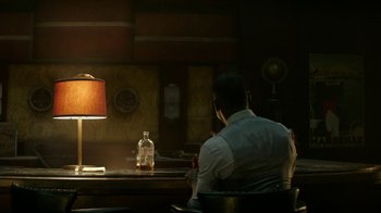 Movie still from “Hotel Artemis” (2018), directed by Drew Pearce – A man sitting at a table in front of a bottle of water; Wide shot, Over the shoulder angle