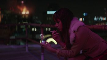 Movie still from “Hotel Artemis” (2018), directed by Drew Pearce – A woman smoking a cigarette while looking at her cell phone; Medium shot, High angle