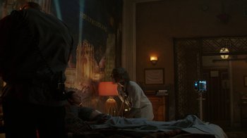 Movie still from “Hotel Artemis” (2018), directed by Drew Pearce – A man and a woman in a room with a painting on the wall behind them; Wide shot, Low angle