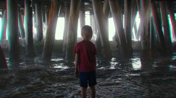 Movie still from “Hotel Artemis” (2018), directed by Drew Pearce – A young boy standing in the water under a pier; Wide shot, Low angle