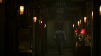 Movie still from “Hotel Artemis” (2018), directed by Drew Pearce – A man in a suit and tie walking down a dark hallway; Wide shot, Low angle