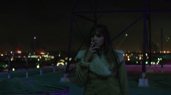 Movie still from “Hotel Artemis” (2018), directed by Drew Pearce – A woman smoking a cigarette while standing in a park; Medium shot, Low angle
