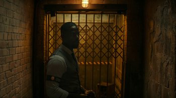 Movie still from “Hotel Artemis” (2018), directed by Drew Pearce – A man standing in front of an iron gate; Medium shot, Over the shoulder angle