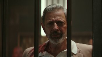 Movie still from “Hotel Artemis” (2018), directed by Drew Pearce – An old man with a beard and a white shirt is behind bars; Close Up shot, Low angle