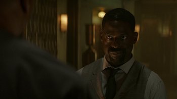 Movie still from “Hotel Artemis” (2018), directed by Drew Pearce – A man in a suit and tie looking into a mirror; Close Up shot, Over the shoulder angle