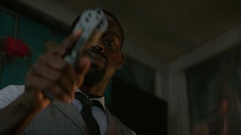 Movie still from “Hotel Artemis” (2018), directed by Drew Pearce – A man in a suit and tie holding a wii controller; Close Up shot, Low angle