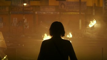 Movie still from “Hotel Artemis” (2018), directed by Drew Pearce – A woman standing in front of a street fire at night; Wide shot, Low angle