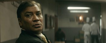 Movie still from “Hotel Mumbai” (2018), directed by Anthony Maras – A person wearing a suit and tie; Close Up shot, Low angle