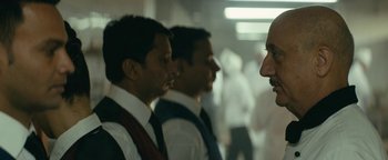 Movie still from “Hotel Mumbai” (2018), directed by Anthony Maras – A group of men standing next to each other in a room; Close Up shot, Over the shoulder angle