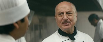 Movie still from “Hotel Mumbai” (2018), directed by Anthony Maras – An older man wearing a white shirt and a black bow tie; Close Up shot, Low angle