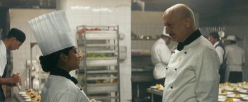 Movie still from “Hotel Mumbai” (2018), directed by Anthony Maras – Two people in a kitchen talking to each other; Medium shot, Over the shoulder angle