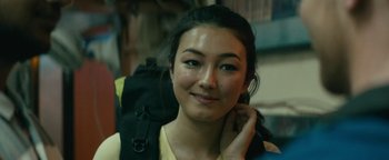 Movie still from “Hotel Mumbai” (2018), directed by Anthony Maras – A woman with a backpack is posing for a picture; Close Up shot, Over the shoulder angle