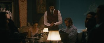 Movie still from “Hotel Mumbai” (2018), directed by Anthony Maras – A man standing at a table with two women; Medium shot, Over the shoulder angle