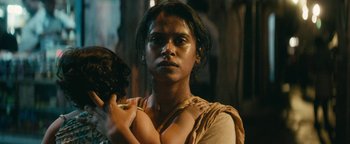 Movie still from “Hotel Mumbai” (2018), directed by Anthony Maras – A young woman with long black hair is holding a child; Close Up shot, Low angle