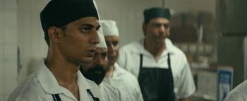 Movie still from “Hotel Mumbai” (2018), directed by Anthony Maras – A group of men standing next to each other in a room; Close Up shot, Over the shoulder angle