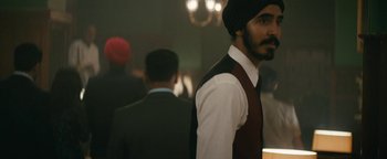 Movie still from “Hotel Mumbai” (2018), directed by Anthony Maras – A man with a turban is standing next to another man in a suit; Close Up shot, Over the shoulder angle