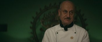 Movie still from “Hotel Mumbai” (2018), directed by Anthony Maras – A man in a chef's outfit standing in front of a green wall; Close Up shot, Low angle