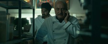Movie still from “Hotel Mumbai” (2018), directed by Anthony Maras – A man in a chef's uniform talking on a phone; Close Up shot, Low angle