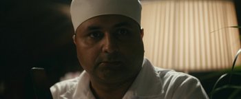 Movie still from “Hotel Mumbai” (2018), directed by Anthony Maras – A person wearing a white hat; Close Up shot, Over the shoulder angle