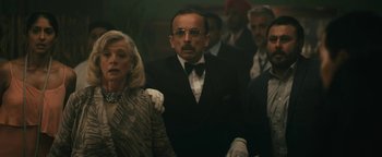 Movie still from “Hotel Mumbai” (2018), directed by Anthony Maras – A group of people standing around each other in a room; Medium shot, Over the shoulder angle