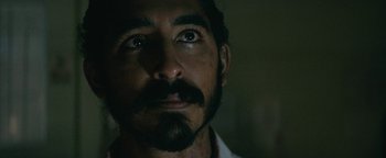Movie still from “Hotel Mumbai” (2018), directed by Anthony Maras – A person with a beard and a mustache; Close Up shot, Over the shoulder angle