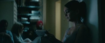 Movie still from “Hotel Mumbai” (2018), directed by Anthony Maras – A woman is looking at a book in a dark room; Close Up shot, Over the shoulder angle