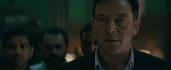 Movie still from “Hotel Mumbai” (2018), directed by Anthony Maras – A person wearing a suit and tie; Close Up shot, Over the shoulder angle