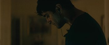 Movie still from “Hotel Mumbai” (2018), directed by Anthony Maras – A person wearing a pair of ear buds; Close Up shot, Low angle
